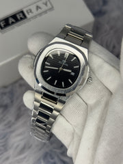 Silver watch with black face held by a gloved hand on a blurred background